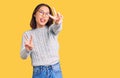 Young beautiful chinese girl wearing casual clothes smiling with tongue out showing fingers of both hands doing victory sign Royalty Free Stock Photo