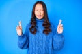 Young beautiful chinese girl wearing casual winter sweater gesturing finger crossed smiling with hope and eyes closed Royalty Free Stock Photo