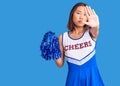 Young beautiful chinese girl wearing cheerleader uniform holding pompom with open hand doing stop sign with serious and confident Royalty Free Stock Photo