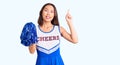 Young beautiful chinese girl wearing cheerleader uniform holding pompom surprised with an idea or question pointing finger with Royalty Free Stock Photo