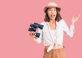 Young beautiful chinese girl wearing explorer hat holding binoculars celebrating victory with happy smile and winner expression Royalty Free Stock Photo