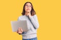 Young beautiful chinese girl wearing glasses holding laptop serious face thinking about question with hand on chin, thoughtful Royalty Free Stock Photo