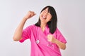 Young beautiful Chinese nurse woman wearing stethoscope over isolated white background very happy and excited doing winner gesture Royalty Free Stock Photo