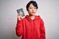 Young beautiful chinese tourist woman on vacation holding canada canadian passport with a confident expression on smart face