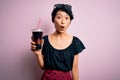 Young beautiful chinese woman drinking cola fizzy beverage using straw over pink background scared in shock with a surprise face,