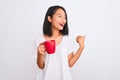 Young beautiful chinese woman drinking cup of coffee over isolated white background pointing and showing with thumb up to the side Royalty Free Stock Photo