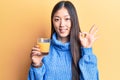 Young beautiful chinese woman drinking glass of orange juice doing ok sign with fingers, smiling friendly gesturing excellent Royalty Free Stock Photo