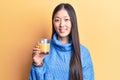 Young beautiful chinese woman drinking glass of orange juice looking positive and happy standing and smiling with a confident Royalty Free Stock Photo