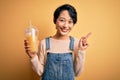 Young beautiful chinese woman drinking healthy orange juice over isolated yellow background surprised with an idea or question Royalty Free Stock Photo