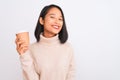 Young beautiful chinese woman drinking paper glass of coffee over isolated white background with a happy face standing and smiling Royalty Free Stock Photo