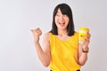 Young beautiful Chinese woman drinking take away coffee over isolated white background pointing and showing with thumb up to the Royalty Free Stock Photo