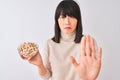 Young beautiful Chinese woman holding bowl with pistachios over isolated white background with open hand doing stop sign with Royalty Free Stock Photo