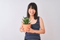 Young beautiful Chinese woman holding cactus pot over isolated white background with a happy face standing and smiling with a Royalty Free Stock Photo