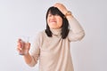 Young beautiful Chinese woman holding glass of water over isolated white background stressed with hand on head, shocked with shame Royalty Free Stock Photo