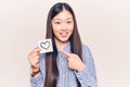 Young beautiful chinese woman holding reminder with heart shape smiling happy pointing with hand and finger