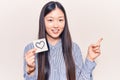 Young beautiful chinese woman holding reminder with heart shape smiling happy pointing with hand and finger to the side