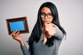 Young beautiful chinese woman holding vintage frame over isolated white background pointing with finger to the camera and to you, Royalty Free Stock Photo