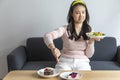 Young beautiful Chinese woman prefer eating salad and using hand push out, deny chocolate cake or dessert.