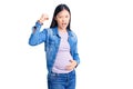 Young beautiful chinese woman pregnant expecting baby angry and mad raising fist frustrated and furious while shouting with anger Royalty Free Stock Photo