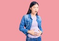 Young beautiful chinese woman pregnant expecting baby angry and mad screaming frustrated and furious, shouting with anger Royalty Free Stock Photo