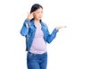 Young beautiful chinese woman pregnant expecting baby confused and annoyed with open palm showing copy space and pointing finger