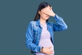 Young beautiful chinese woman pregnant expecting baby covering eyes with hand, looking serious and sad