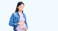 Young beautiful chinese woman pregnant expecting baby depressed and worry for distress, crying angry and afraid