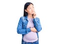 Young beautiful chinese woman pregnant expecting baby with hand on chin thinking about question, pensive expression Royalty Free Stock Photo