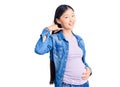 Young beautiful chinese woman pregnant expecting baby smiling doing phone gesture with hand and fingers like talking on the