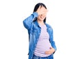 Young beautiful chinese woman pregnant expecting baby smiling and laughing with hand on face covering eyes for surprise