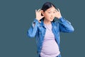 Young beautiful chinese woman pregnant expecting baby trying to hear both hands on ear gesture, curious for gossip