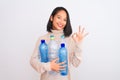 Young beautiful chinese woman recycling plastic bottles over isolated white background doing ok sign with fingers, excellent