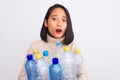 Young beautiful chinese woman recycling plastic bottles over isolated white background scared in shock with a surprise face,