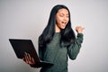 Young beautiful chinese woman using laptop standing over isolated white background pointing and showing with thumb up to the side Royalty Free Stock Photo