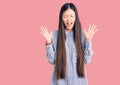 Young beautiful chinese woman wearing casual shirt celebrating mad and crazy for success with arms raised and closed eyes