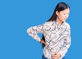 Young beautiful chinese woman wearing casual shirt suffering of backache, touching back with hand, muscular pain Royalty Free Stock Photo