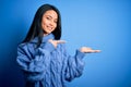 Young beautiful chinese woman wearing casual sweater over isolated blue background amazed and smiling to the camera while Royalty Free Stock Photo