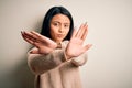 Young beautiful chinese woman wearing casual sweater over isolated white background Rejection expression crossing arms and palms Royalty Free Stock Photo