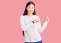 Young beautiful chinese woman wearing casual sweater smiling and looking at the camera pointing with two hands and fingers to the