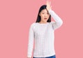 Young beautiful chinese woman wearing casual sweater surprised with hand on head for mistake, remember error