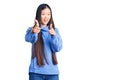 Young beautiful chinese woman wearing casual turtleneck sweater pointing fingers to camera with happy and funny face