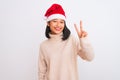 Young beautiful chinese woman wearing Christmas Santa hat over isolated white background smiling looking to the camera showing Royalty Free Stock Photo