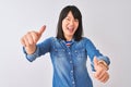 Young beautiful chinese woman wearing denim shirt over isolated white background approving doing positive gesture with hand, Royalty Free Stock Photo