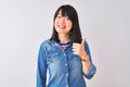 Young beautiful chinese woman wearing denim shirt over isolated white background doing happy thumbs up gesture with hand Royalty Free Stock Photo