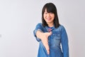 Young beautiful chinese woman wearing denim shirt over isolated white background smiling friendly offering handshake as greeting Royalty Free Stock Photo