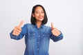 Young beautiful chinese woman wearing denim shirt standing over isolated white background approving doing positive gesture with Royalty Free Stock Photo