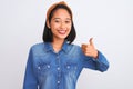Young beautiful chinese woman wearing denim shirt standing over isolated white background doing happy thumbs up gesture with hand Royalty Free Stock Photo