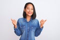 Young beautiful chinese woman wearing denim shirt standing over isolated white background success sign doing positive gesture with Royalty Free Stock Photo