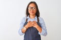 Young beautiful chinese woman wearing glasses and apron over isolated white background smiling with hands on chest with closed Royalty Free Stock Photo