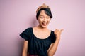 Young beautiful chinese woman wearing golden crown of king over isolated pink background smiling with happy face looking and Royalty Free Stock Photo